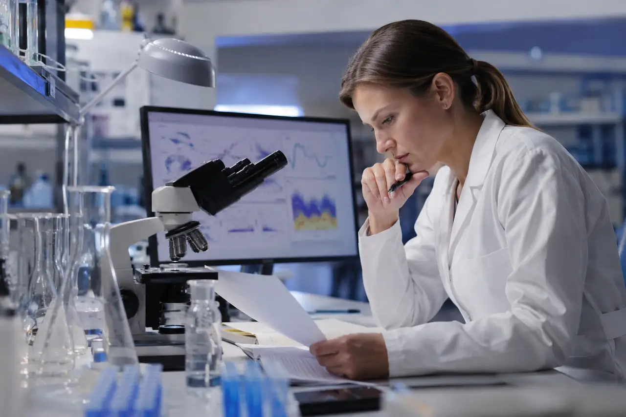 Científica analizando resultados junto a un microscopio en un laboratorio moderno